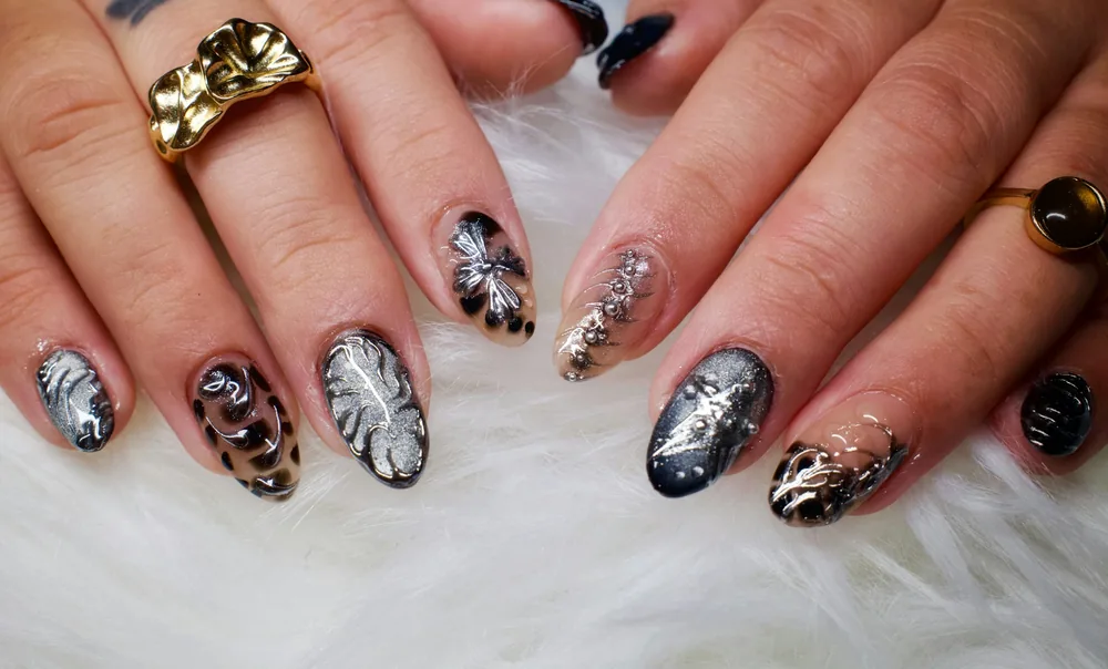 Manos con uñas decoradas con estampado de leopardo, hojas y purpurina